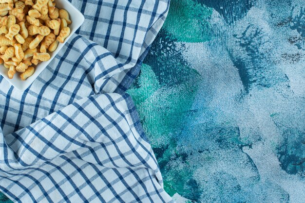 Cracker fish in bowl on tea towel , on the blue table.