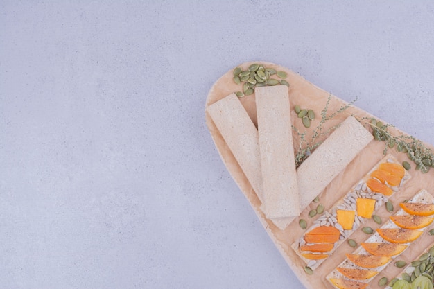 Cracker sandwiches with herbs and fruits on a wooden board