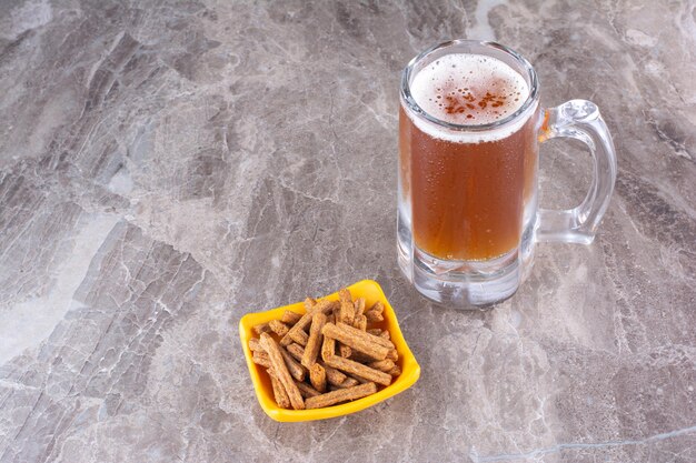 Crackers and glass of cold beer on marble surface. High quality photo