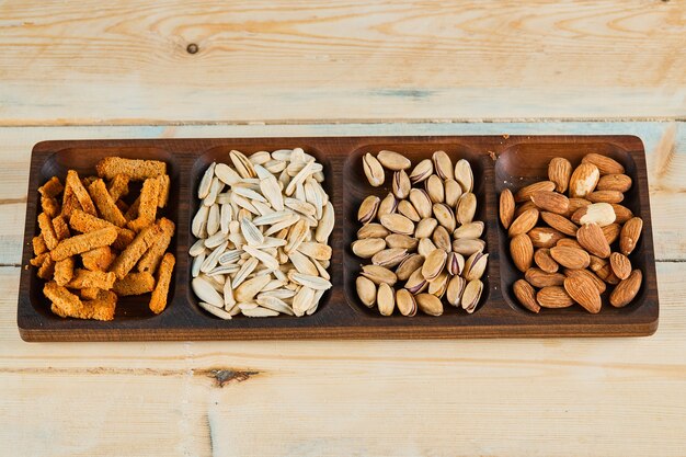 Crackers, pistachios and almonds on wooden platter.