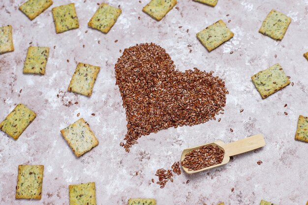 Crackers in shape of heart from linen seeds with olive oil,linen seeds and greens,top view