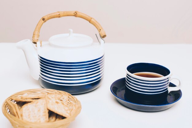 Crackers; tea cup and teapot on white desk