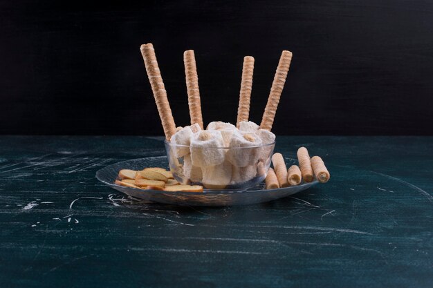 Crackers and waffle sticks with turkish lokum in a glass platter on black background