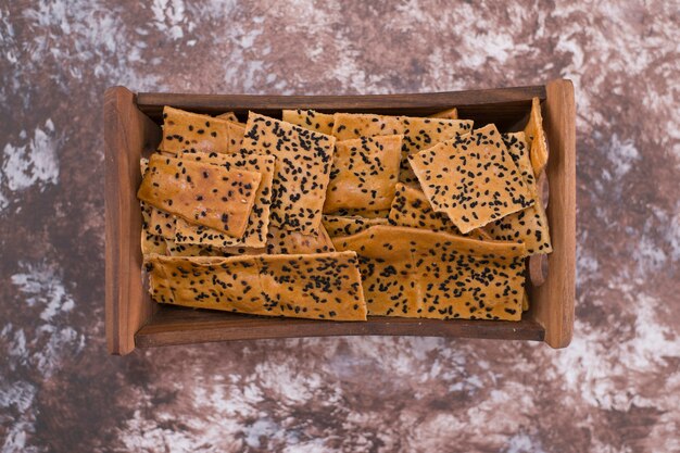 Crackers with black cumin on them in wooden tray in the center