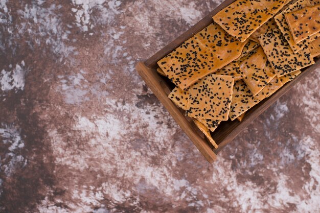 Crackers with black cumin on them in wooden tray on the top corner.