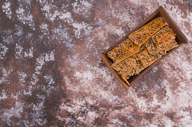 Crackers with black cumin on them in wooden tray on the top corner