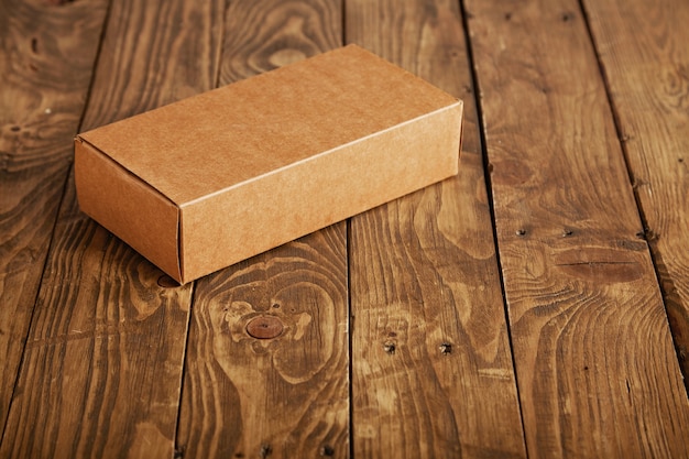 Free photo craft unlabeled cardboard package box presented on stressed brushed wooden table, closeup