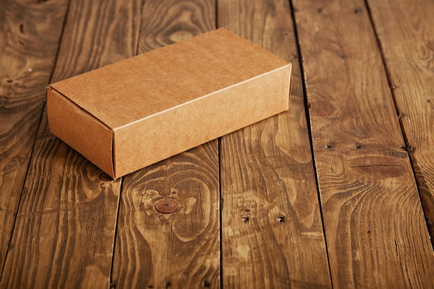 ストレスのかかったブラシをかけられた木製のテーブル、クローズアップで提示されたラベルのない段ボールのパッケージボックスを作成します。