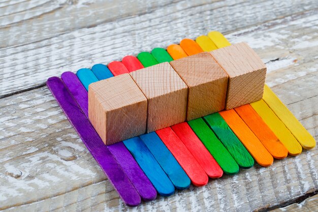 Crafting concept with sticks, wooden cubes on wooden background high angle view.