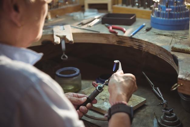 Craftswoman using blow torch in workshop