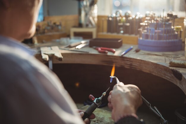 워크숍에서 블로우 토치를 사용하는 craftswoman