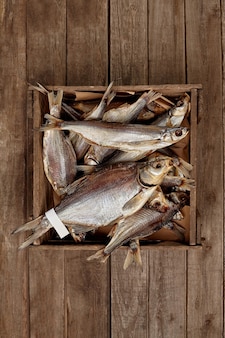 Crate with various sundried fish on wooden planks background