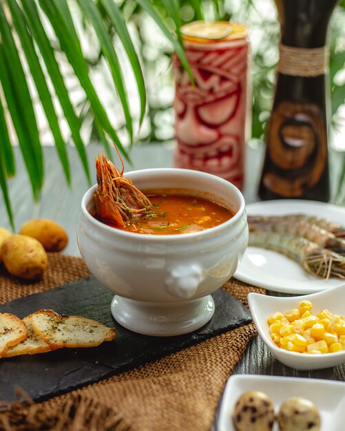 Crayfish soup with toasts and corns on black board on burlap tablecloth