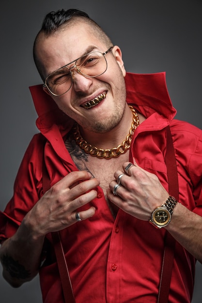 Free photo crazy man in red t shirt glasses and tattoo on hands isolated on grey.