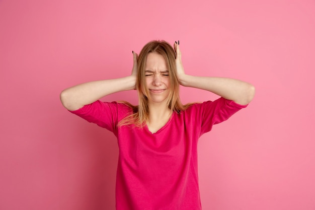 Crazy shocked, upset. Caucasian young woman's portrait isolated on pink  wall, monochrome. Beautiful female model. 