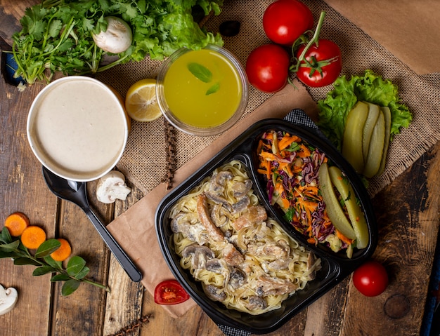 Cream mushroom soup in disposable cup bowl served with green vegetables, mushroom cream stew and vegetable salad   