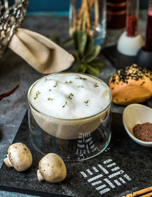 Cream mushroom soup with herbs in transparent bowl.