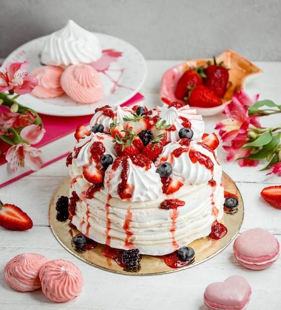Cream and strawberry meringue cake sprinkled with strawberry syrup