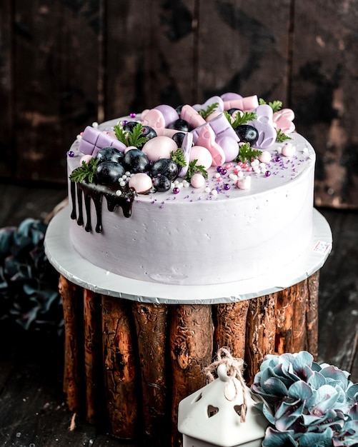 Creamy cake in lilac topped with pink lilac decorations and grapes