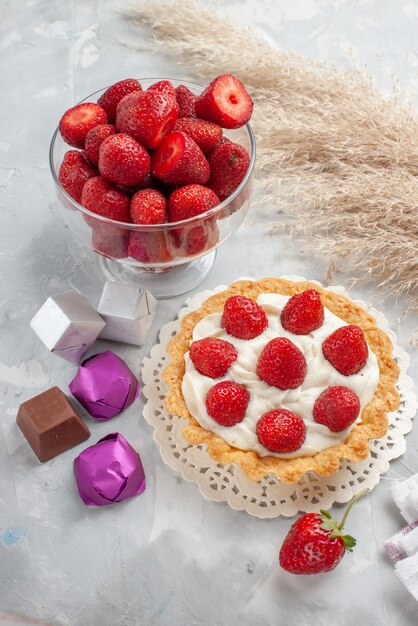 creamy cake with fresh red strawberries and chocolate candies cake on white-light desk, cake fruit berry biscuit cream sweet