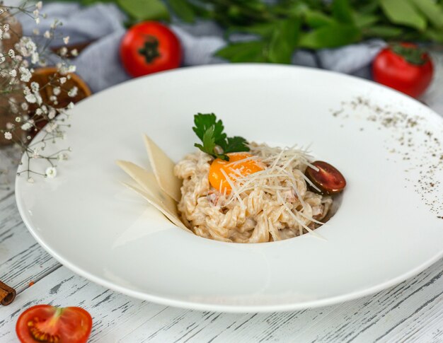 Creamy fusilli pasta garnished with parmesan slices, parsley and black cherry tomato