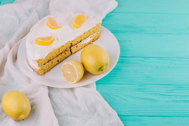 나무 테이블에 레몬과 하얀 접시에 크림 레몬 케이크