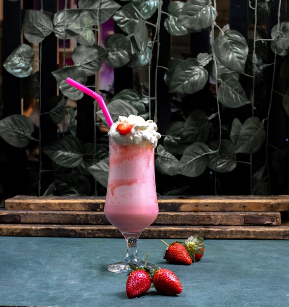 Creamy milky cocktail with strawberry syrup on the blue table