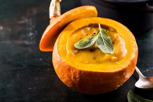 Creamy pumpkin soup puree in the whole squash on table ready to eat