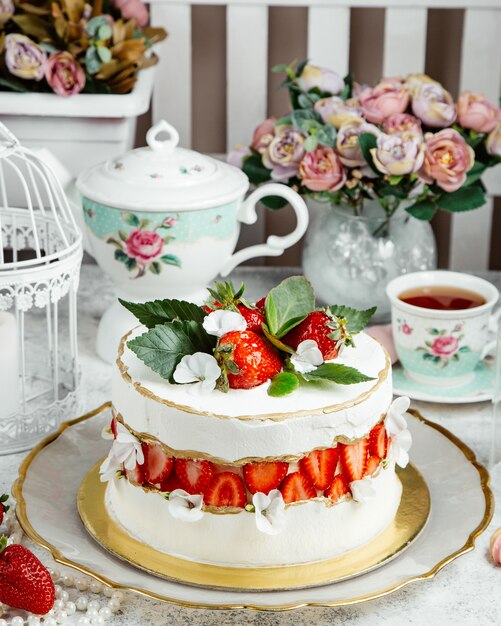 Creamy strawberry cake topped with fresh strawberries and leaves