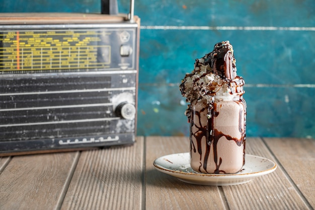 Creamy vanilla milky shake with chocolate sauce in a white saucer