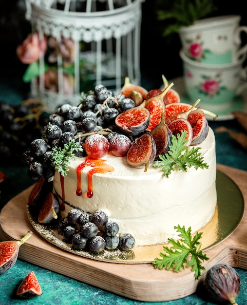 Creamy white cake decorated with fig halves and grape