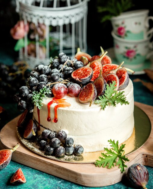 Creamy white cake decorated with fig halves and grape