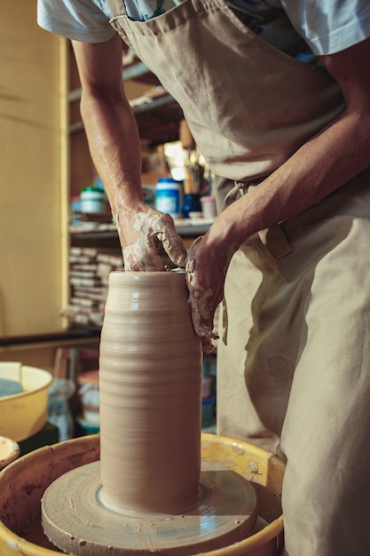 Creating a jar or vase of white clay close-up. Master crock. Man hands making clay jug macro.