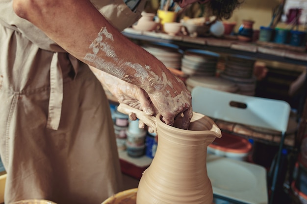 Foto gratuita creazione di un barattolo o vaso di close-up di argilla bianca. mastro coccio. mani dell'uomo che fanno la macro della brocca dell'argilla.