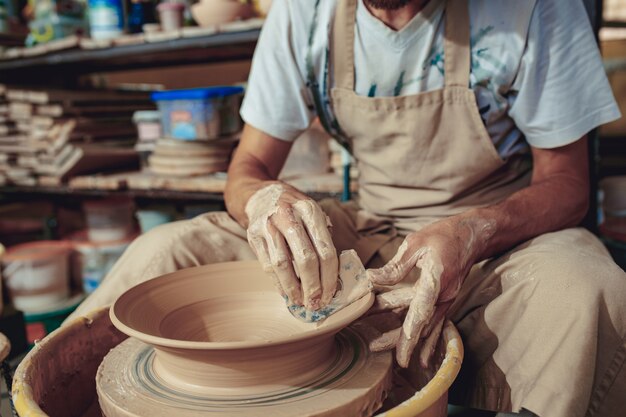 Creating a jar or vase of white clay close-up. Master crock. Man hands making clay jug macro.