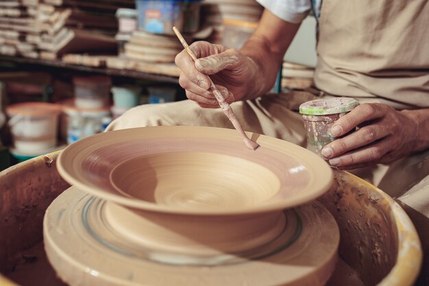 Creating a jar or vase of white clay close-up. Master crock. Man hands making clay jug macro.