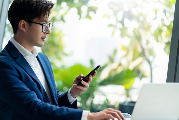 Creative agency smart glasses asian male formal cloth conversation with smartphone freelance working with laptop at coworking area office space with freshness with blur office background