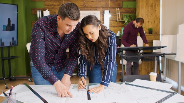 Creative architects working on blueprints in modern office space