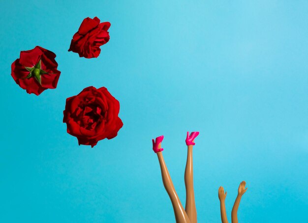 Creative arrangement with red roses and doll legs in high heels minimal summer concept