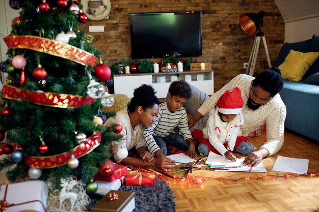 집에서 크리스마스를 보내는 동안 종이에 색칠하는 창의적인 흑인 가족
