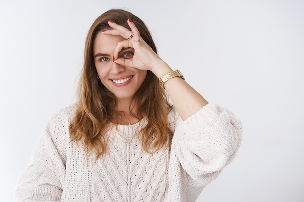 Creative charismatic flirty good-looking charming european woman playing you having fun smiling broadly white teeth making circle okay ok gesture looking through curious pleased, white background