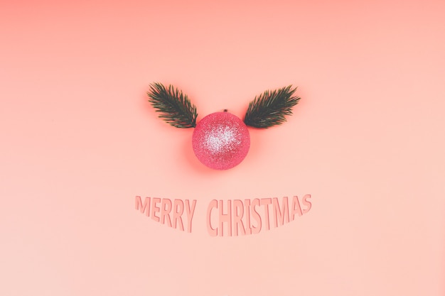 Креативная рождественская минималистичная композиция. елочный шар на розовом фоне. розовая блестящая новогодняя игрушка с ветками елки. вид сверху, плоский стиль, пустое место для текста