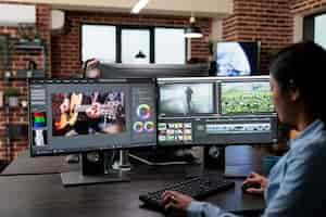 Free photo creative company professional movie footage editor sitting at multi monitor workstation while editing film frames. expert videographer improving video quality using specialized software.