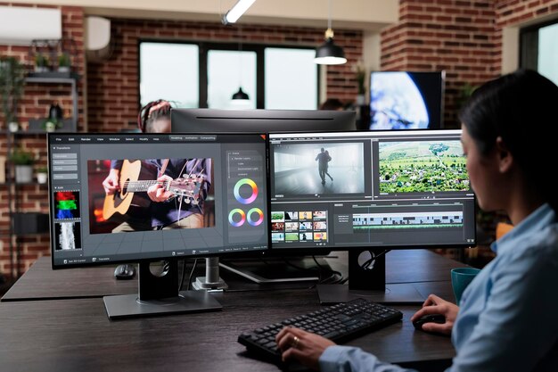 Creative company professional movie footage editor sitting at multi monitor workstation while editing film frames. Expert videographer improving video quality using specialized software.