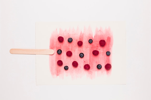 Creative composition of popsicle from fragrant currant and raspberry on stick