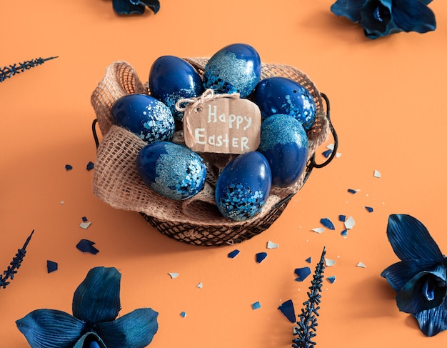 Creative Easter layout made of colorful eggs and flowers on blue background. Circle wreath flat lay concept. The concept of the Easter holidays.