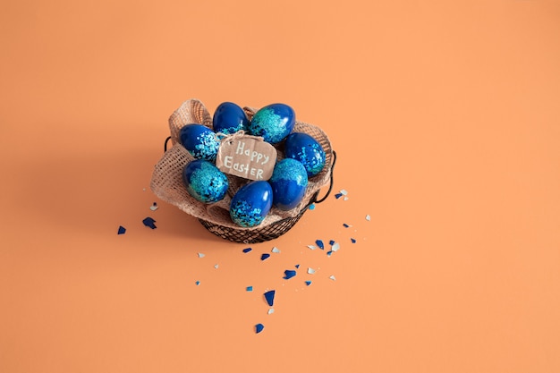 Creative Easter layout made of colorful eggs and flowers on blue background. Circle wreath flat lay concept. The concept of the Easter holidays.
