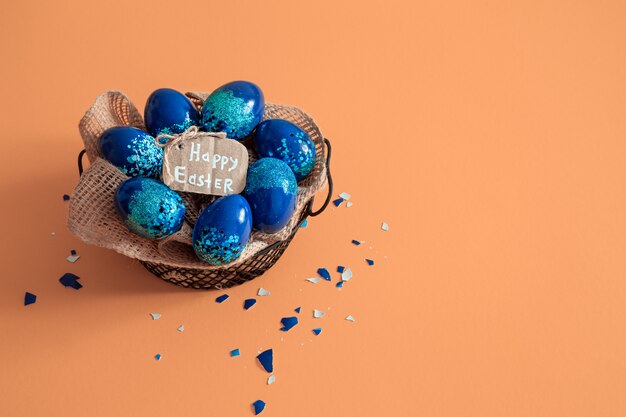 Creative Easter layout made of colorful eggs and flowers on blue.