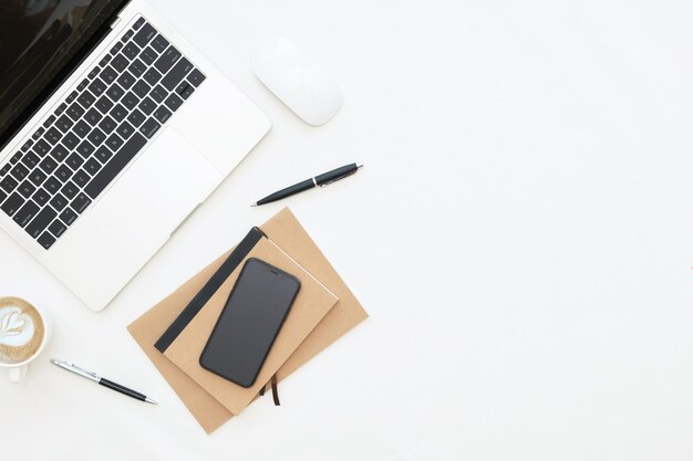 Creative flat lay design of workspace desk with laptop, laptop, blank notebook, smartphone and stationery with copy space background