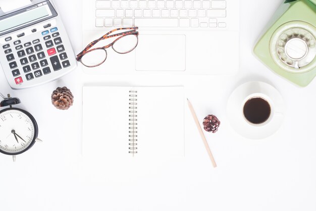 Creative flat lay of workspace with white laptop, retro style telephone, coffee cup and blank notebook for text